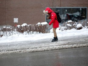 A pedestrian makes a video of herself sliding down Peel St. after freezing rain in Montreal on Jan. 3, 2017.