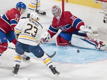 Montreal Canadiens goalie Carey Price, right, reaches for the puck as Canadiens defenceman Alexei Emelin, left, and Buffalo Sabres centre Sam Reinhart, right, battle during the first period of their NHL hockey match in Montreal on Tuesday, Jan. 31, 2017.