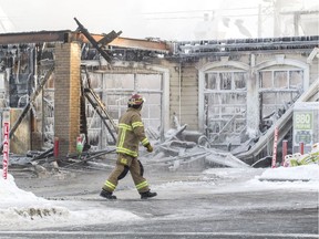 A Laval firefighter surveys the scene of a fire that destroyed several businesses at René-Laennac Blvd. and Lausanne St. in Laval, north of Montreal, Monday January 9, 2017.  There were no injuries and police suspect arson.
