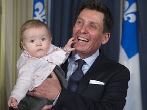 New Quebec Treasury Board president Pierre Moreau holds his eight-month-old granddaughter Jeanne after he was sworn in, Monday, Jan. 16, 2017 at the legislature in Quebec City.