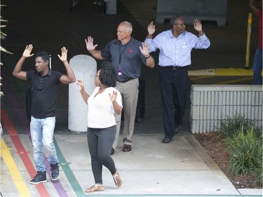 People leave a garage area with their hands up in the air outside Fort Lauderdale–Hollywood International Airport, after a shooter opened fire inside a terminal of the airport, killing several people and wounding others before being taken into custody, Friday, Jan. 6, 2017, in Fort Lauderdale, Fla.