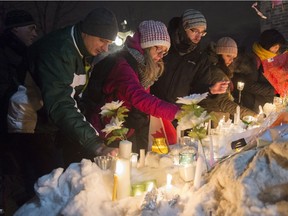 People place candles during a vigil Monday, January 30, 2017 in Quebec City. A shooting at a Quebec City mosque left six people dead and eight others injured Sunday.