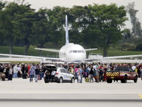 People stand on the tarmac at the Fort Lauderdale-Hollywood International Airport after a shooter opened fire inside a terminal of the airport, killing several people and wounding others before being taken into custody, Friday, Jan. 6, 2017, in Fort Lauderdale, Fla.