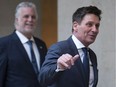 Quebec cabinet Minister Pierre Moreau waves as he heads to his first cabinet meeting since he got sick, Wednesday, December 21, 2016, at the Premier's office in Quebec City. Quebec Premier Philippe Couillard smiles as he walks behind. Moreau was sick with meningitis and encephalitis on January 28, 2016, and was unable to work.