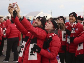 Short Track speed skaters Charles Hamelin and Marianne St-Gelais pose for a picture with their teammates in the background before the Canadian team welcome ceremony at the athlete's village for the Sochi Winter Olympics in Sochi, Russia, Wednesday, Feb. 5, 2014.