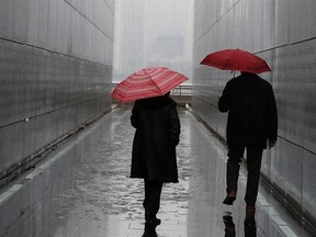 FILE - In this Tuesday, Jan. 17, 2017, file photo, a couple walks through the Empty Sky Memorial during a rainy day at Liberty State Park, in Jersey City, N.J. An age difference in your relationship doesn‚Äôt just mean your favorite bands are from different decades. Even a small difference in years between two people can affect when you retire, how much you need to save and how those savings are invested. (AP Photo/Julio Cortez, File)