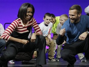FILE - In this Feb. 9, 2012, file photo, first lady Michelle Obama and Bob Harper of &ampquot;The Biggest Loser,&ampquot; right in blue shirt, do the Interlude dance during a Let&#039;s Move event with children from Iowa schools at the Wells Fargo Arena in Des Moines, Iowa. Harper tells TMZ he suffered a heart attack and was hospitalized for several days in February 2017. (AP Photo/Carolyn Kaster, File)