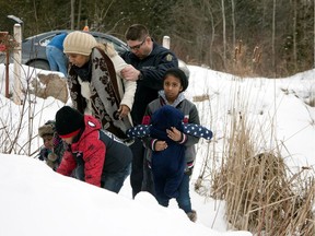 A woman who told police that she and her family were from Sudan is taken into custody by a Royal Canadian Mounted Police (RCMP) officer after arriving by taxi and walking across the U.S.-Canada border into Hemmingford, Quebec, Canada February 12, 2017.