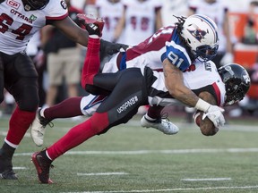 Ottawa Redblacks running back Travon Van is tackled by Montreal Alouettes defensive tackle Alan-Michael Cash (91)during second quarter CFL football action, in Montreal on Thursday, June 30, 2016.