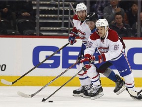 Montreal Canadiens center Andrew Shaw, front, reaches to control the puck in front of Colorado Avalanche centre Mikhail Grigorenko and Canadiens defenceman Nikita Nesterov, back, during the second period of an NHL hockey game Feb. 7, 2017, in Denver.