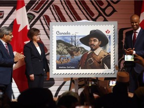 Canada Post President Deepak Chopra (left), Minister of Public Services, Judy Foote (centre) and Immigration Minister Ahmed Hussen (right) unveil a stamp of Mathieu de Costa believed to be the first person of African descent to reach Canada in 1608 at a reception to celebrate Black History Month in Gatineau, Quebec, Monday February 6, 2017.