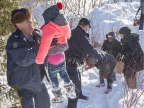 Family members from Somalia are helped into Canada by RCMP officers along the U.S.-Canada border near Hemmingford, Que., on Friday, Feb. 17, 2017.