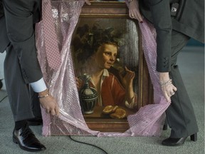 FBI agents unwrap "Young Man As Bacchus" by Jan Franse Verzijl before before the start of a ceremony to formally return the painting to representatives of the Max and Iris Stern Foundation, Wednesday, Feb. 8, 2017, at the Museum of Jewish Heritage in New York. Federal investigators recovered the 1630 oil painting in a 2015 art fair.