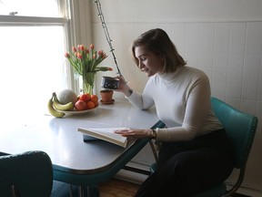 Linn Blomkvist reads a book while having a coffee in her bright kitchen.