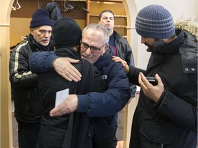 Mohamed Labidi, centre, vice-president of the Centre Culturel Islamique de Québec in Quebec City, is comforted by another man on Wednesday February 1, 2017, after some people were allowed inside for the first time since a mass shooting at the centre on Sunday.