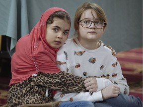 Seven year-old Imane Omari, left, and 11 year-old Myka Miller, who are friends from St. Gabriel elementary school in Pointe-Saint-Charles, listen to speeches at the Khadijah Masjid Islamic Centre in Pointe-Saint-Charles during a day of open doors at Mosques in Montreal on Sunday, Feb. 12, 2017.