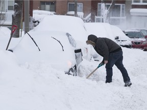 A motorist digs out his car on Marette St. in St-Laurent on Monday February 13, 2017, following a snowstorm that dumped up to 23cm of snow in some places.