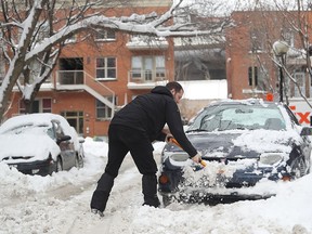 Simon Lesage shovels the snow in order to free his car from the ice on Saint-Philippe street in the south west of Montreal on February 16, 2017.