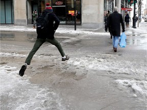 A pedestrian takes a running leap over a puddle at the corner of Ste-Catherine and Metcalfe Sts. in Montreal Feb. 8, 2017.