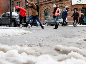 Pedestrians leap over a puddle at the corner of Ste-Catherine and Mansfield Sts. in Montreal on Wednesday, Feb. 8, 2017.