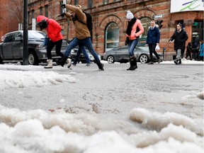 Pedestrians leap over a puddle at the corner of Ste-Catherine and Mansfield Sts. in Montreal Feb. 8, 2017.