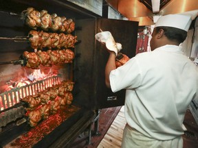 A cook takes chickens out of the rotisserie at Chalet Bar-B-Q, a decades-old Montreal favourite.