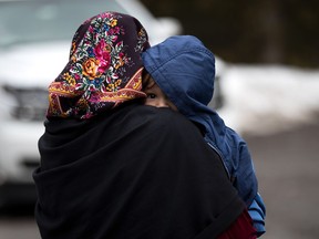 A mother and child from Turkey wait to be put into a police vehicle by the Royal Canadian Mounted Police after crossing the U.S.-Canada border Feb. 23, 2017, in Hemmingford.