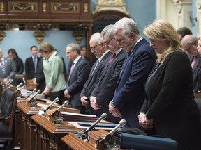 Members of the National Assembly in Quebec City observe a minute of silence in honour of the victims of the Quebec mosque shooting and two former members of the legislature who passed away, as the legislature resumes for its spring session on Tuesday, Feb. 7, 2017. From right, Deputy Premier Lise Theriault, Quebec Premier Philippe Couillard, Quebec government legislature leader Jean-Marc Fournier, Quebec Finance Minister Carlos Leitao and Quebec Public Security Minister and Municipal Affairs Minister Martin Coiteux look down.