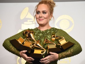 Adele poses in the press room with her trophies, including the top two Grammys of Album and Record of the Year for her blockbuster hit "Hello" and the album "25", during the 59th Annual Grammy music Awards on Sunday, Feb. 12, 2017, in Los Angeles.