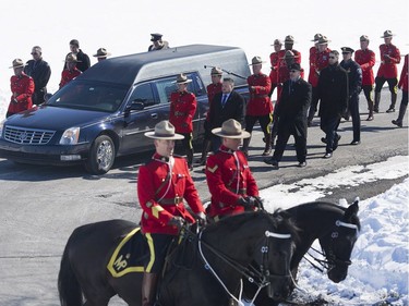 RCMP officers lead the procession next to the hearse containing the remains of RCMP Constable Richer Dubuc ahead of his funeral on the the St-Jean Garrison Military Base in Saint-Jean-sur-Richelieu, Que., on Saturday, March 18, 2017. Constable Dubuc died while on duty on March 6.