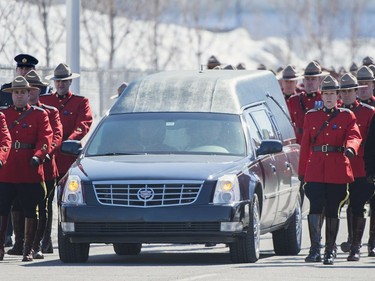 RCMP officers lead the procession next to the hearse containing the remains of RCMP Constable Richer Dubuc ahead of his funeral on the the St-Jean Garrison Military Base in Saint-Jean-sur-Richelieu, Que., on Saturday, March 18, 2017. Constable Dubuc died while on duty on March 6.