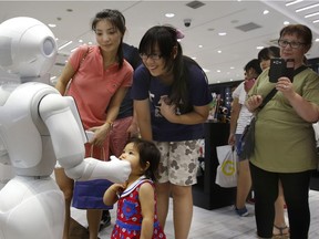 Future ready? Shoppers talk to SoftBank Corp.'s companion robot Pepper, equipped with a "heart" designed to not only recognize human emotions but react with simulations of anger, joy and irritation, at a store in Tokyo in July 2016.