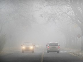 Cars drive through the fog on Victoria St. in the Lachine borough of Montreal on Friday, Nov. 18, 2016.