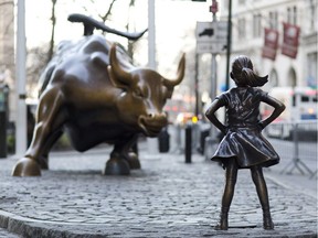 In this March 22, 2017 photo, the Charging Bull and Fearless Girl statues are sit on Lower Broadway in New York. Since 1989 the bronze bull has stood in New York City's financial district as an image of the might and hard-charging spirit of Wall Street. But the installation of the bold girl defiantly standing in the bull's path has transformed the meaning of one of New York's best-known public artworks. Pressure is mounting on the city to let the Fearless Girl stay.