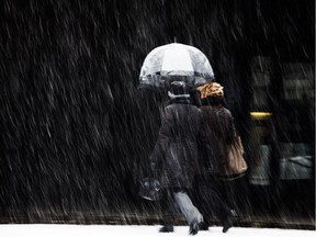 Pedestrians with an umbrella walk past the courthouse during a spring snowfall in Montreal April 12, 2013.