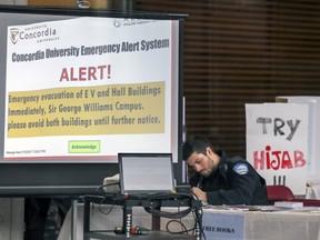 A police officer makes notes next to some Muslim displays in the lobby of Concordia University's EV Building on in Montreal following a bomb threat targeting Muslim students Wednesday March 1, 2017.