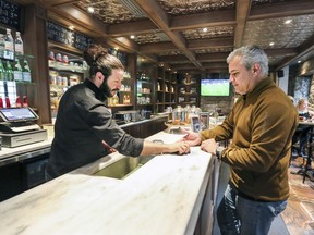 Barista David Mariani takes payment from customer Marcos Lopez at Café Olimpico's new location in the William Gray Hotel in Old Montreal.