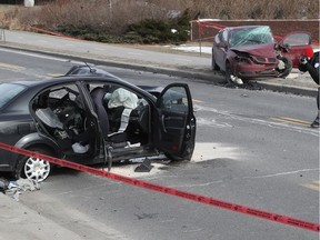 A Montreal police officer takes pictures at the scene of accident on Jacques-Bizard Blvd. on Sunday March 12, 2017. One person has been pronounced dead and two others are in critical condition.