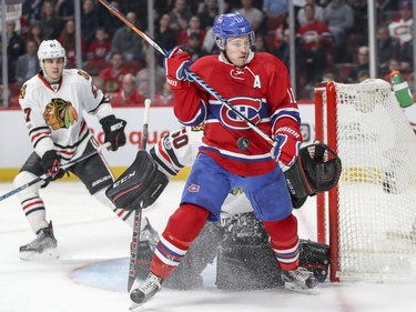 Montreal Canadiens Brendan Gallagher gets hit by the puck as he backs into Chicago Blackhawks goalie Corey Crawford during first period of National Hockey League game in Montreal Tuesday March 14, 2017. Hawks Trevor van Riemsdyk watches at left.