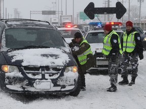 Officers from the Surete du Quebec and Montreal police help to clear vehicles from Highway 520 near Cavendish Rd. March 15, 2017 following a massive snowstorm that left many motorists stranded overnight.