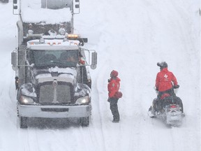 SQ officers on snowmobiles, and safety crews try to clear up Highway 13 near Côte-de-Liesse Rd. March 15, 2017, following massive snow storm that left many motorists stranded overnight.