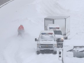 SQ officers on snowmobiles, and safety crews try to clear up Highway 13 near Côte-de-Liesse Rd. March 15, 2017, following massive snow storm that left many motorists stranded overnight.