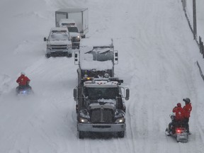 SQ officers on snowmobile, and safety crews try to clear up Highway 13 near Cote de Liesse road on Wednesday March 15, 2017 following massive snow storm that left many motorists stranded overnight.