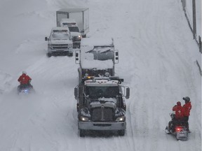 Sûreté du Québec officers on snowmobiles reach vehicles stranded on Highway 13 near Côte-de-Liesse Rd. on March 15, 2017.