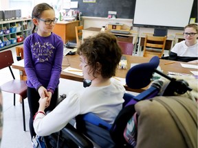 Jacqueline Burt, left, holds Erika Ellingsen's hand after pairing up with her for a group assignment at the Mackay Centre School.