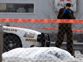 An SQ officer takes pictures at the scene where a body was found on the side of Highway 13 in Laval on Tuesday, March 21, 2017