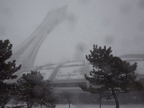 Wind and blowing snow almost obscure the Olympic stadium and its tower in March 2014.