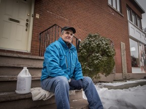 Eddy Kalil outside his home in Montreal, on Friday, March 24, 2017.  Khalil is fighting a borough-issued fine that requires him to keep his building clean of graffiti, he has with him a container of graffiti removal liquid that costs $100, it is becoming expensive as each time he cleans the wall behind him it gets covered again, he has also installed lattice for plants in hope that they also will help stop the graffiti artists from tagging his wall.