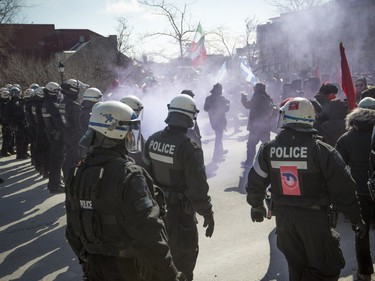 As smoke from smoke bomb fills the air, police watch to keep anti-racism protesters from approaching protesters consisting of far-right groups at a demonstration in front of Montreal city hall Saturday, March 4, 2017.