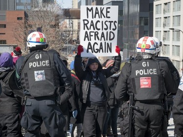 Police watch to keep anti-racism protesters from approaching protesters consisting of far-right groups at a demonstration in front of Montreal city hall Saturday, March 4, 2017.